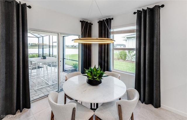 dining area featuring a water view, plenty of natural light, and light tile patterned floors