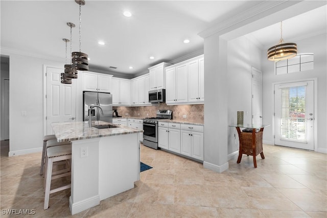 kitchen featuring pendant lighting, light stone counters, stainless steel appliances, and an island with sink