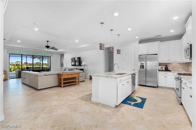 kitchen with ceiling fan, an island with sink, decorative light fixtures, white cabinets, and appliances with stainless steel finishes