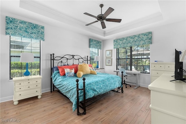 bedroom featuring ceiling fan, a raised ceiling, light wood-type flooring, and crown molding