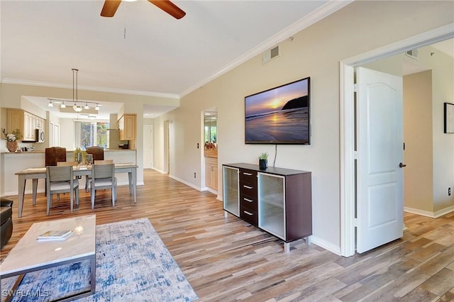 living room with light hardwood / wood-style flooring, ornamental molding, and ceiling fan