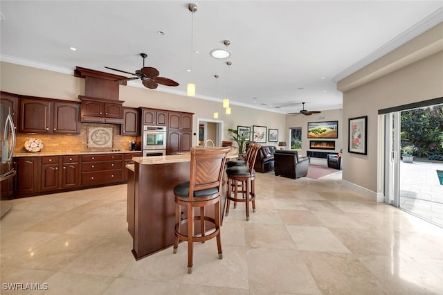 kitchen with a kitchen bar, plenty of natural light, decorative light fixtures, and ornamental molding