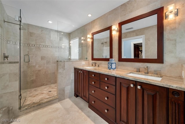 bathroom with vanity, an enclosed shower, and tile walls