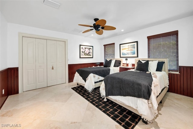 bedroom featuring ceiling fan, a closet, and wood walls