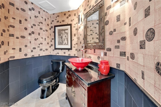 bathroom featuring tile patterned floors, vanity, tile walls, and toilet