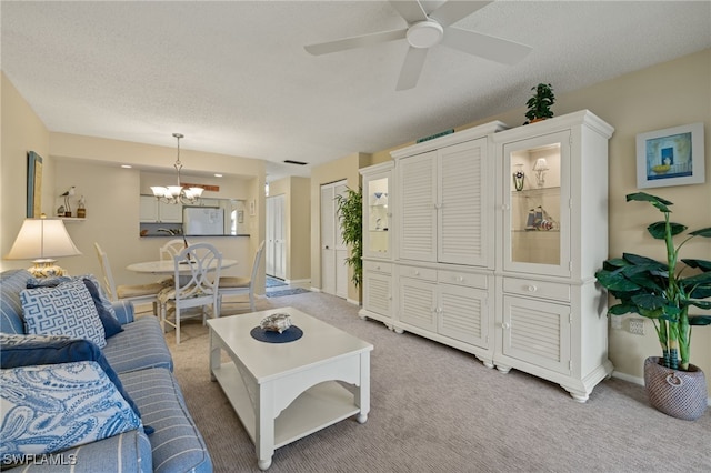 carpeted living room with a textured ceiling and ceiling fan with notable chandelier