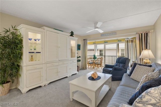 carpeted living room with ceiling fan and a textured ceiling