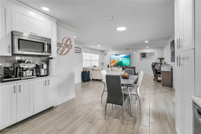 dining area with light wood-type flooring and ornamental molding