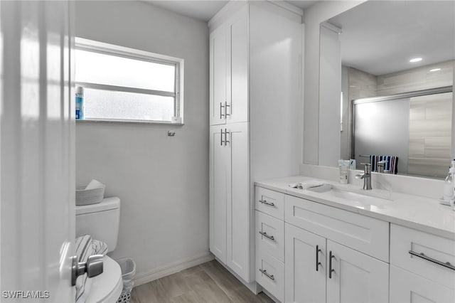 bathroom featuring hardwood / wood-style floors, vanity, toilet, and walk in shower