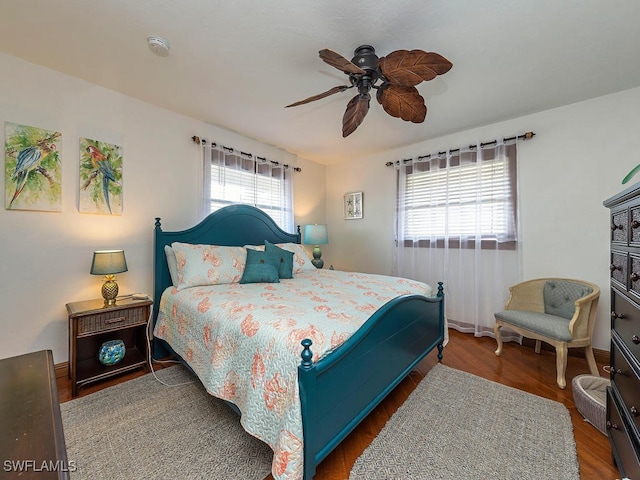 bedroom featuring ceiling fan, dark hardwood / wood-style floors, and multiple windows