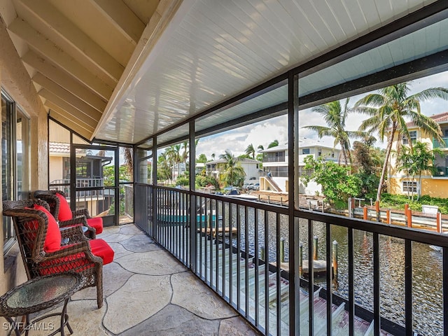 sunroom / solarium with a water view and lofted ceiling