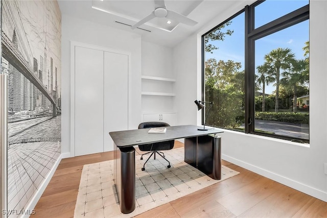 office area with a wealth of natural light, a ceiling fan, and light wood-style floors