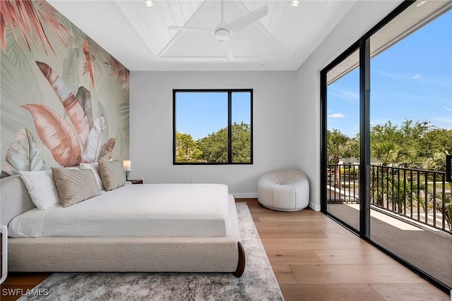 bedroom featuring baseboards, access to outside, wood finished floors, and multiple windows