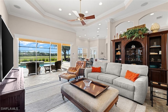 living room featuring a tray ceiling, ceiling fan, and ornamental molding