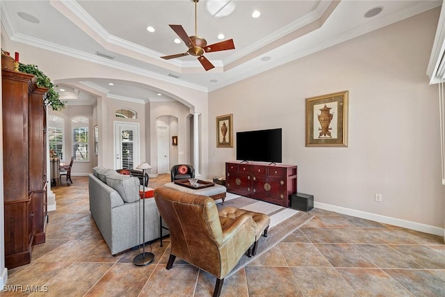 living room with a tray ceiling, crown molding, and ceiling fan