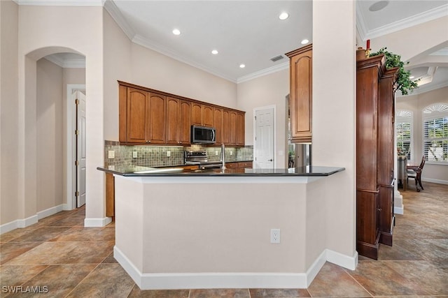 kitchen featuring decorative backsplash, kitchen peninsula, crown molding, and appliances with stainless steel finishes