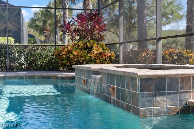 view of pool with pool water feature and glass enclosure