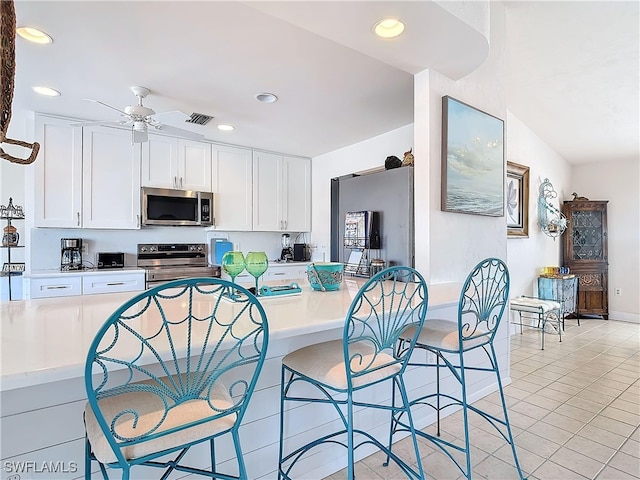 kitchen featuring light tile patterned floors, stainless steel appliances, white cabinetry, and ceiling fan