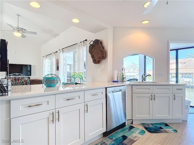 kitchen with sink, white cabinets, stainless steel dishwasher, and lofted ceiling