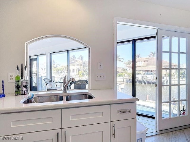 kitchen featuring a water view, a wealth of natural light, sink, and white cabinets