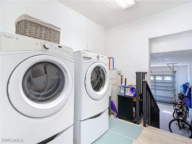 clothes washing area featuring hardwood / wood-style flooring, washer and clothes dryer, and water heater