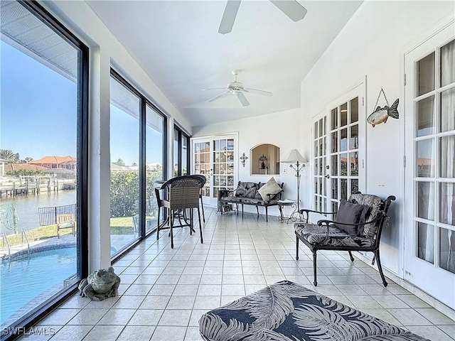 sunroom with ceiling fan and a water view