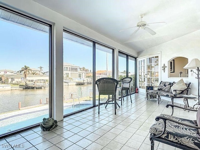 sunroom featuring ceiling fan and a water view