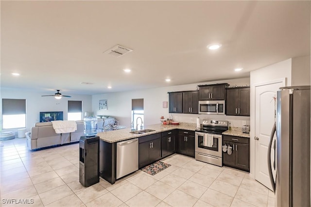 kitchen featuring dark brown cabinetry, sink, light stone counters, kitchen peninsula, and appliances with stainless steel finishes