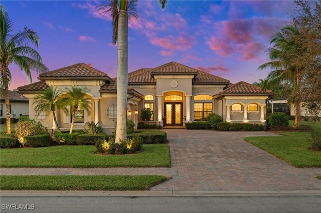 mediterranean / spanish-style house with a lawn and french doors