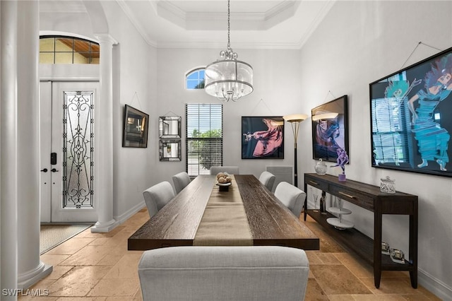 dining area featuring a high ceiling, a tray ceiling, ornate columns, and ornamental molding