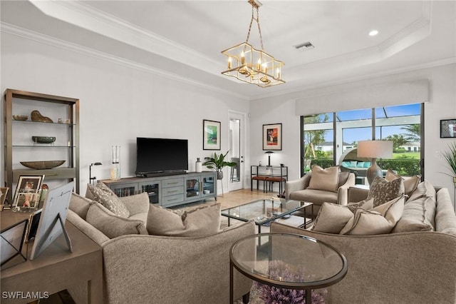 living room with a raised ceiling, crown molding, hardwood / wood-style floors, and an inviting chandelier