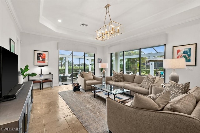 living room with a raised ceiling, a chandelier, and ornamental molding