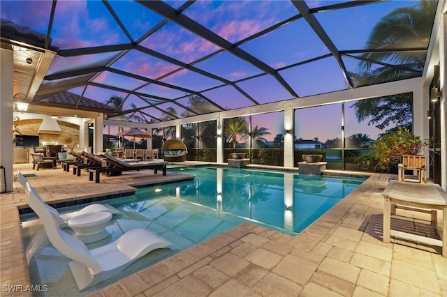 pool at dusk featuring a patio area and a lanai