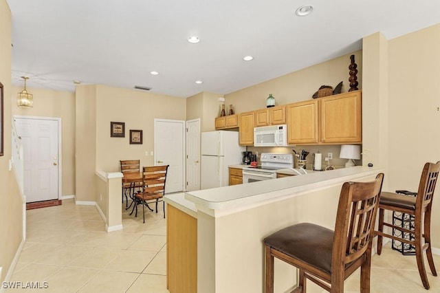 kitchen featuring kitchen peninsula, light brown cabinetry, light tile patterned flooring, and white appliances