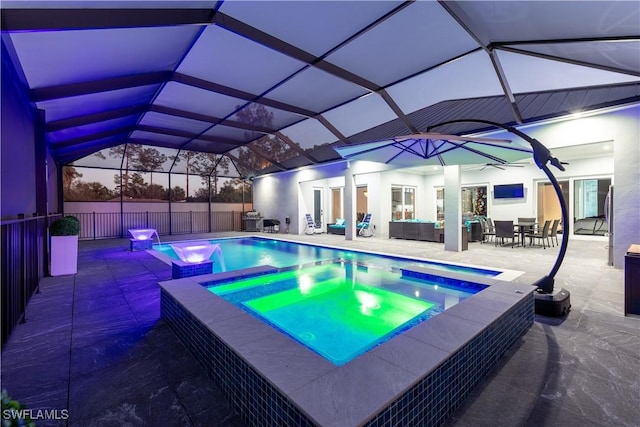 pool at dusk featuring glass enclosure, an in ground hot tub, a patio, and an outdoor hangout area