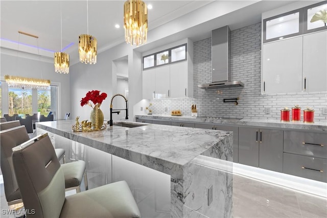 kitchen with white cabinets, hanging light fixtures, wall chimney exhaust hood, and sink