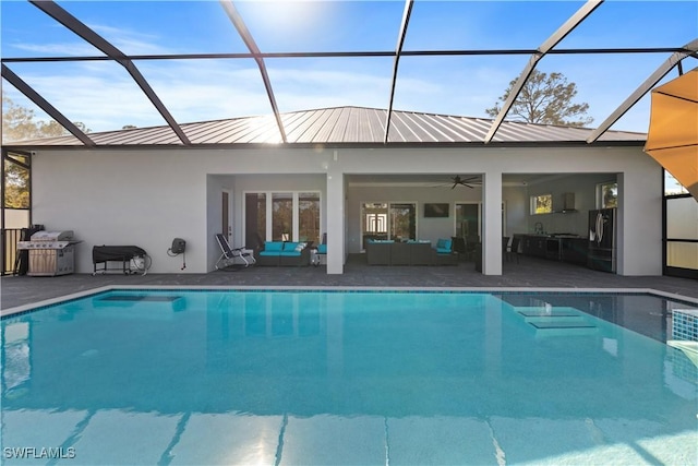 view of swimming pool featuring glass enclosure, ceiling fan, a patio, and an outdoor hangout area