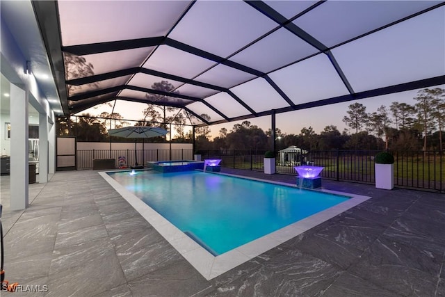 pool at dusk featuring a lanai, an in ground hot tub, and a patio