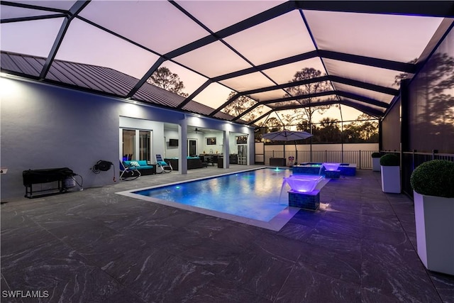 pool at dusk featuring a lanai, a jacuzzi, an outdoor living space, pool water feature, and a patio area