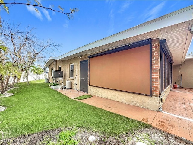 view of side of property with central AC unit and a lawn