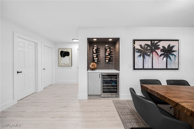 office with light hardwood / wood-style flooring, beverage cooler, and indoor bar