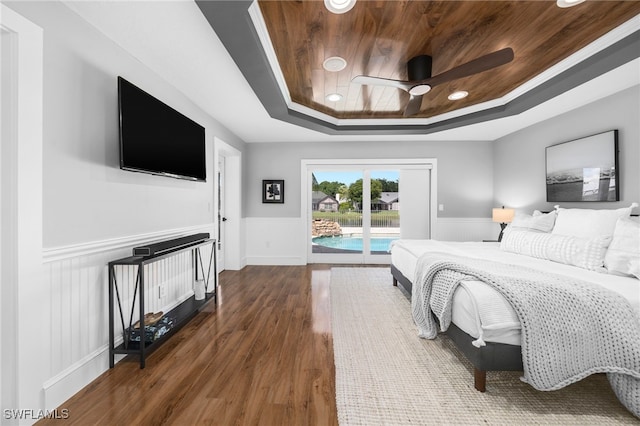 bedroom featuring access to exterior, a tray ceiling, ceiling fan, and dark wood-type flooring