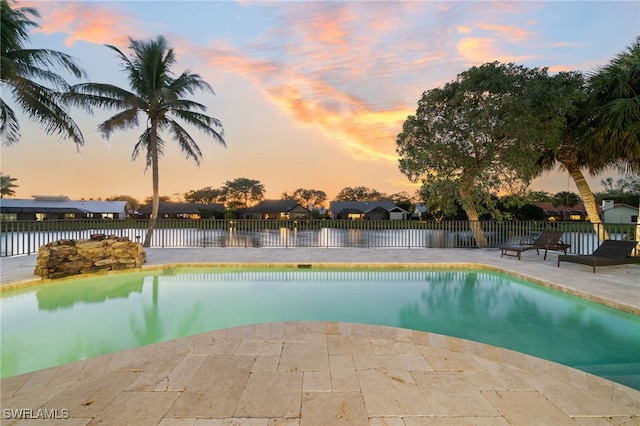 pool at dusk featuring a patio area