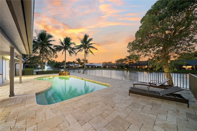 pool at dusk with a patio and a water view