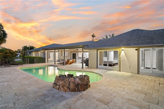 pool at dusk with french doors, a patio, and ceiling fan