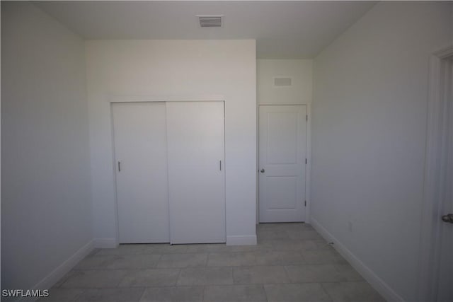 unfurnished bedroom featuring a closet and light tile patterned floors