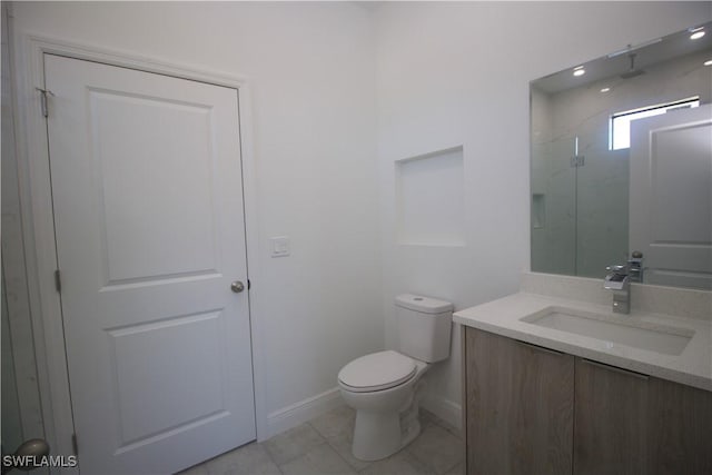 bathroom featuring tile patterned floors, vanity, tiled shower, and toilet