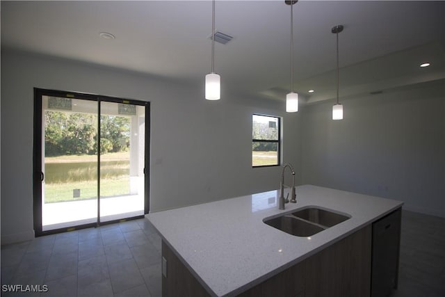 kitchen with sink, decorative light fixtures, plenty of natural light, and an island with sink