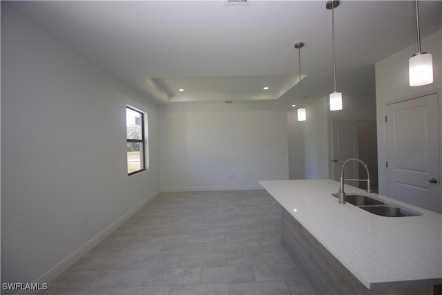 kitchen with tile patterned floors, a raised ceiling, sink, hanging light fixtures, and light stone counters