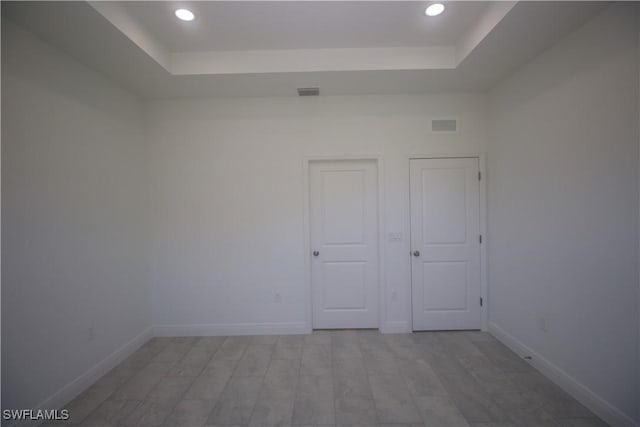 unfurnished room featuring a tray ceiling and light hardwood / wood-style flooring